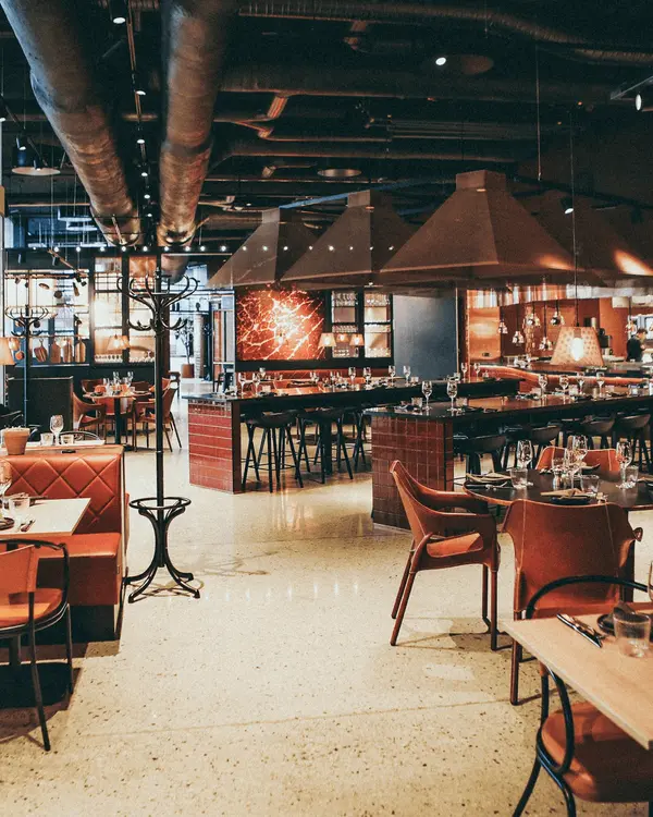 An empty dining room of warm timber tables and chairs
