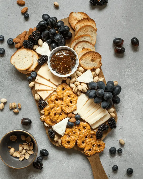 An unbranded cheese and preserves board on a pale surface